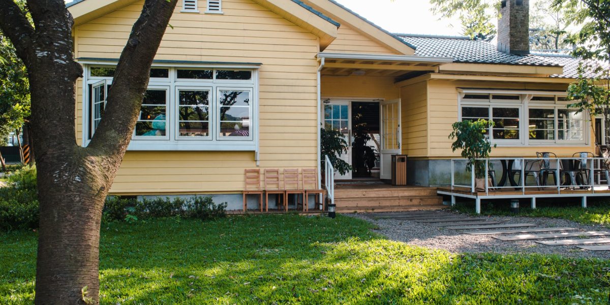 A charming yellow house with wooden windows and green grassy garden